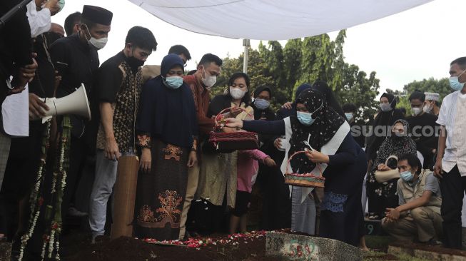 Keluarga menaburkan bunga di makam legenda bulutangkis Indonesia, Markis Kido di TPU Kebon Nanas, Cipinang, Jakarta, Selasa (15/6/2021). [Suara.com/Angga Budhiyanto]