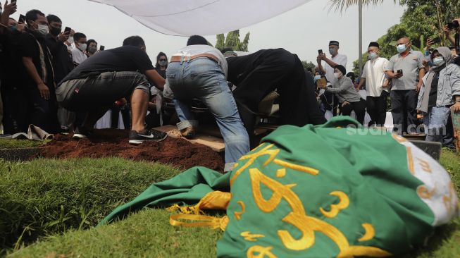 Keluarga menguburkan jenazah legenda bulutangkis Indonesia, Markis Kido di TPU Kebon Nanas, Cipinang, Jakarta, Selasa (15/6/2021). [Suara.com/Angga Budhiyanto]