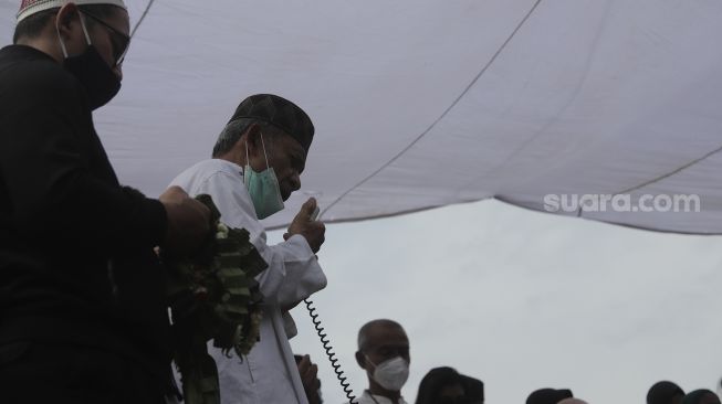 Keluarga dan kerabat memanjatkan doa saat prosesi penguburan jenazah legenda bulutangkis Indonesia, Markis Kido di TPU Kebon Nanas, Cipinang, Jakarta, Selasa (15/6/2021). [Suara.com/Angga Budhiyanto]