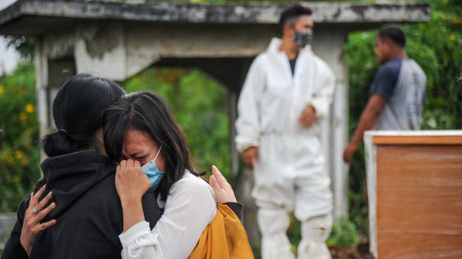 Keluarga menangis saat menyaksikan pemakaman jenazah dengan protokol COVID-19 di TPU Cikadut, Bandung, Jawa Barat, Selasa (15/6/2021). ANTARA FOTO/Raisan Al Farisi