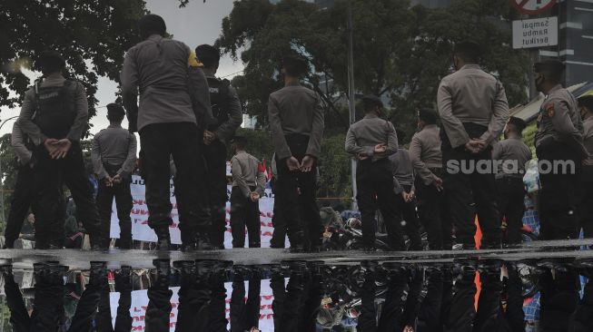 Refleksi personel kepolisian melakukan pengamanan saat massa mahasiswa melakukan aksi unjuk rasa di sekitar Gedung Komisi Pemberantasan Korupsi (KPK), Jakarta, Rabu (16/6/2021). [Suara.com/Angga Budhiyanto] 