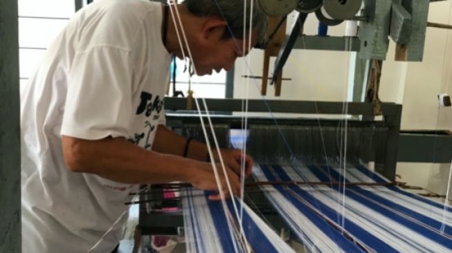 Proses menenun benang oleh pengerajin tenun Palembang [Fitria/Suara.com]