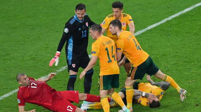 Connor Roberts dari Wales bentrok dengan Burak Yilmaz dari Turki pada pertandingan Euro 2020, di Stadion Olimpiade Baku, Baku, Azerbaijan, Kamis (17/6/2021) dini hari WIB.  TOLGA BOZOGLU / KOLAM RENANG / AFP
