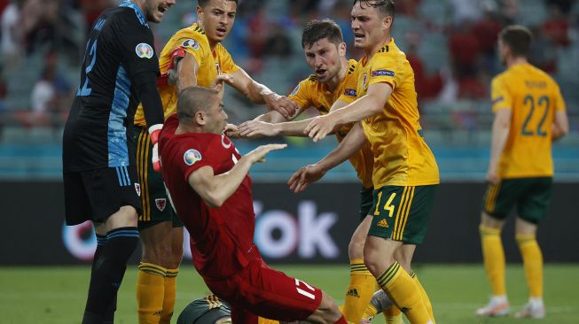 Connor Roberts dari Wales bentrok dengan Burak Yilmaz dari Turki pada pertandingan Euro 2020, di Stadion Olimpiade Baku, Baku, Azerbaijan, Kamis (17/6/2021) dini hari WIB.  TOLGA BOZOGLU / KOLAM RENANG / AFP
