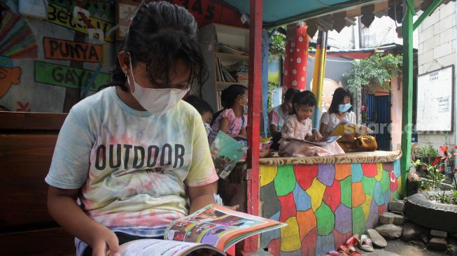 Sejumlah anak membaca buku di Bale Buku, Gang Dendrit, Cakung, Jakarta Timur, Jumat (18/6/2021).[Suara.com/Dian Latifah]