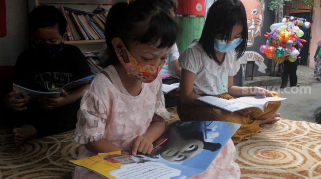 Sejumlah anak membaca buku di Bale Buku, Gang Dendrit, Cakung, Jakarta Timur, Jumat (18/6/2021).[Suara.com/Dian Latifah]