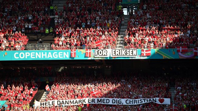 Suporter Denmark membentangkan spanduk dukungan untuk Christian Eriksen saat laga Piala Eropa 2020 Grup B antara Denmark melawan Belgia di Parken Stadium, Copenhagen, Kamis (17/6/2021).  [AFP/Photo]