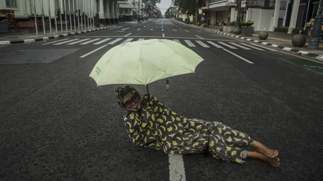 Cosplayer hantu tidur di tengah ruas jalan protokol kawasan Asia Afrika yang ditutup di Bandung, Jawa Barat, Jumat (18/6/2021).  ANTARA FOTO/Novrian Arbi