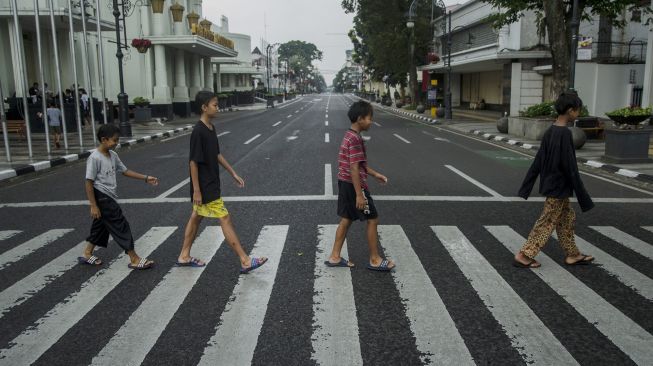 Sejumlah anak menyeberang di ruas jalan protokol kawasan Asia Afrika yang ditutup di Bandung, Jawa Barat, Jumat (18/6/2021). ANTARA FOTO/Novrian Arbi