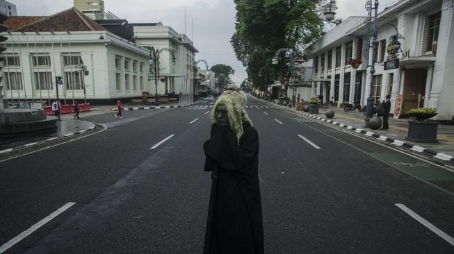 

Cosplayer hantu tidur di tengah ruas jalan protokol kawasan Asia Afrika yang ditutup di Bandung, Jawa Barat, Jumat (18/6/2021).  ANTARA FOTO/Novrian Arbi