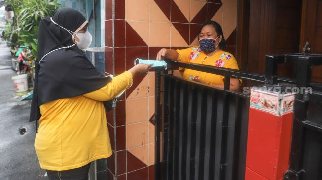 Warga membagikan masker ke warga lainnya di Kampung Tangguh Jaya RW 13 Bidara Cina, Jakarta Timur, Sabtu (19/6/2021). [Suara.com/Alfian Winanto]