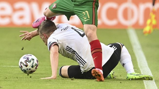 Pemain depan Portugal Diogo Jota (atas) mencoba menghindari bek Jerman Matthias Ginter selama pertandingan sepak bola Grup F UEFA EURO 2020 antara Portugal dan Jerman di Allianz Arena, Munich pada (19/6/2021). [CHRISTOF STACHE / POOL / AFP]