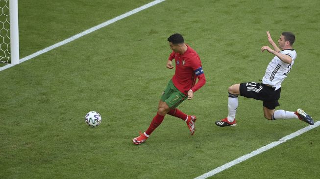 Pemain depan Portugal Cristiano Ronaldo (kiri) mencetak gol pertama mereka selama pertandingan sepak bola Grup F UEFA EURO 2020 antara Portugal dan Jerman di Allianz Arena, Munich pada (19/6/2021). [Matthias Hangst / POOL / AFP]