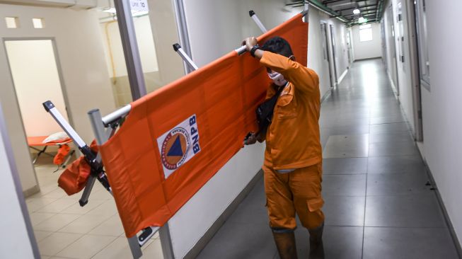 Petugas Penanganan Prasarana dan Sarana Umum (PPSU) mengangkat velbed di salah satu tower di Rumah Susun Nagrak, Cilincing, Jakarta Utara, Senin (21/6/2021). [ANTARA FOTO/M Risyal Hidayat]