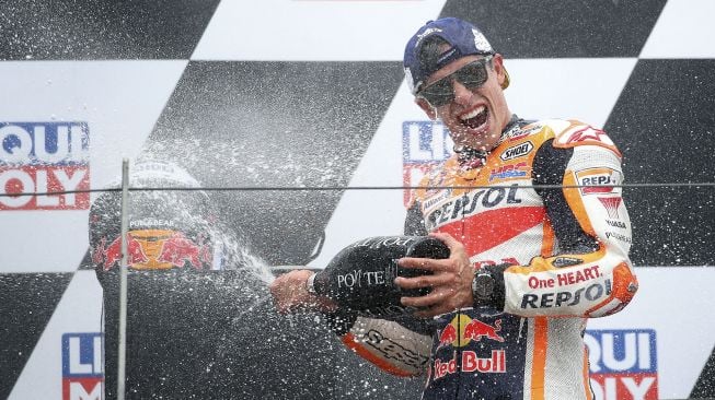 Pembalap Honda Spanyol Marc Marquez merayakan di podium dengan Champagne setelah memenangkan Grand Prix MotoGP Jerman di sirkuit balap Sachsenring, Hohenstein-Ernstthal, Jerman Timur, pada (20/6/2021). [Ronny HARTMANN / AFP]