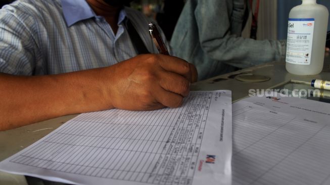 Calon penumpang KRL menulis data diri sebelum mengikuti swab test antigen secara acak di Stasiun Bekasi, Jawa Barat, Senin (21/6/2021). [Suara.com/Dian Latifah]