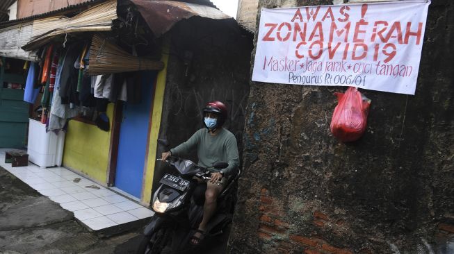 Warga berkendara di zona merah COVID-19 RT 006 RW 01, Gandaria Selatan, Cilandak, Jakarta Selatan, Senin (21/6/2021). [ANTARA FOTO/Sigid Kurniawan]