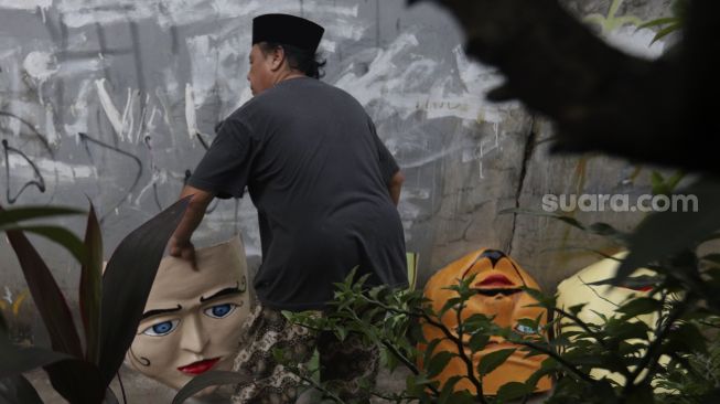 Seniman menyelesaikan pembuatan ondel-ondel Betawi ukuran besar di kawasan Jagakarsa, Jakarta Selatan, Senin (21/6/2021). [Suara.com/Angga Budhiyanto]