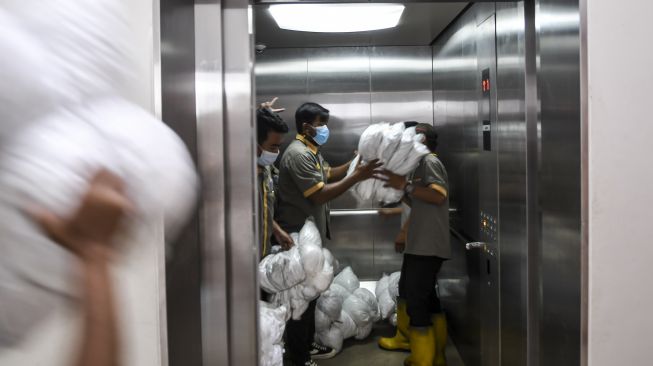 Petugas membawa bantal di salah satu tower di Rumah Susun Nagrak, Cilincing, Jakarta Utara, Senin (21/6/2021). [ANTARA FOTO/M Risyal Hidayat]