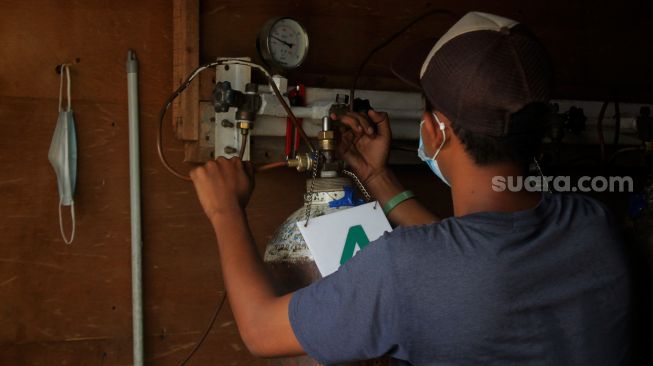 Pekerja mengisi ulang tabung oksigen yang dibawa pelanggan di depot pengisian oksigen, Manggarai, Jakarta, Selasa (22/6/2021). [Suara.com/Dian Latifah
