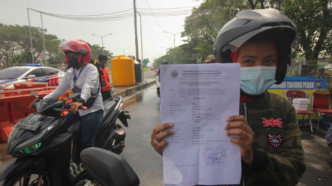 Warga dari Pulau Madura menunjukkan dokumen Surat Izin Keluar Masuk (SIKM) di akses keluar Jembatan Suramadu, Surabaya, Jawa Timur, Senin (21/6/2021). ANTARA FOTO/Didik Suhartono