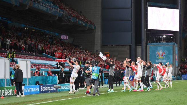 
Para pemain Denmark bersama para staf merayakan kepastian timnya lolos 16 besar Euro 2020 usai menang 4-1 atas Rusia, Selasa (22/6/2021) dini hari WIB. (Foto: Stuart FRANKLIN/AFP)