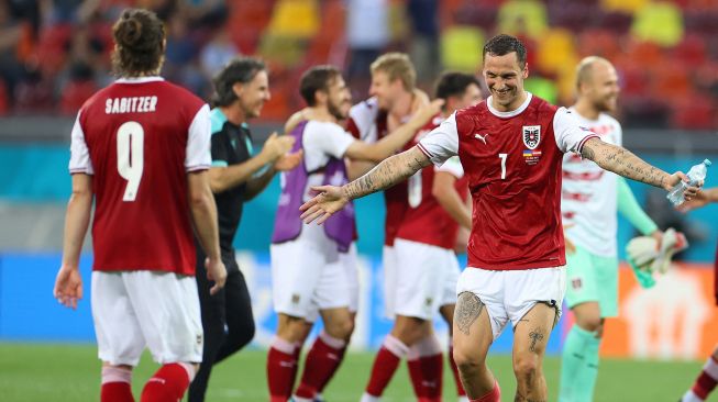 Para pemain Austria bersama para staf merayakan kepastian timnya lolos 16 besar Euro 2020 di National Arena, Senin (21/6/2021).  [Foto/AFP]