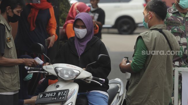 Warga memeriksa suhu tubuh pesepeda motor yang melintas masuk ke zona merah COVID-19 RT 006 RW 01, Gandaria Selatan, Cilandak, Jakarta, Selasa (22/6/2021). [Suara.com/Angga Budhiyanto]