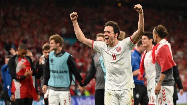 Para pemain Denmark bersama para staf merayakan kepastian timnya lolos 16 besar Euro 2020 usai menang 4-1 atas Rusia, Selasa (22/6/2021) dini hari WIB. (Foto: Stuart FRANKLIN/AFP)