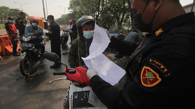 Petugas memeriksa dokumen Surat Izin Keluar Masuk (SIKM) milik warga yang akan masuk ke Surabaya di akses keluar Jembatan Suramadu, Surabaya, Jawa Timur, Senin (21/6/2021). ANTARA FOTO/Didik Suhartono