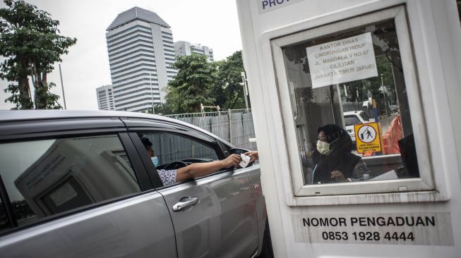 Pengendara mobil menyerahkan karcis parkir ke petugas di lapangan IRTI Monas, Jakarta Pusat, Jakarta, Rabu (23/6/2021).  ANTARA FOTO/Aprillio Akbar