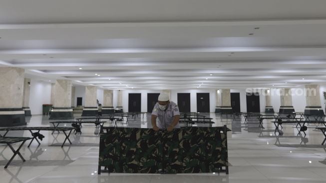 Petugas menyiapkan tempat tidur bagi warga yang akan menjalani isolasi mandiri di Masjid Raya KH Hasyim Asy'ari, Jakarta, Rabu (23/6/2021). [Suara.com/Angga Budhiyanto]