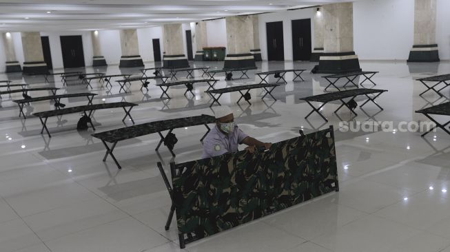 Petugas menyiapkan tempat tidur bagi warga yang akan menjalani isolasi mandiri di Masjid Raya KH Hasyim Asy'ari, Jakarta, Rabu (23/6/2021). [Suara.com/Angga Budhiyanto]