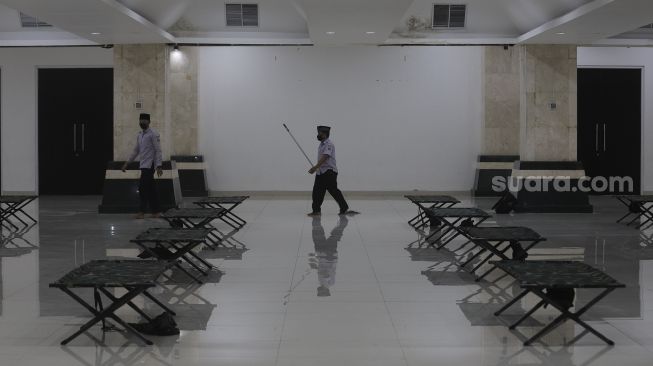 Petugas berjalan di dalam ruangan yang akan dijadikan tempat isolasi mandiri di Masjid Raya KH Hasyim Asy'ari, Jakarta, Rabu (23/6/2021). [Suara.com/Angga Budhiyanto]