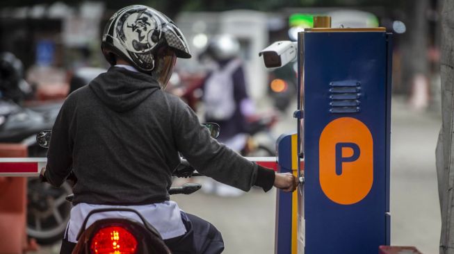 Pengendara sepeda motor mengambil karcis parkir di lapangan IRTI Monas, Jakarta Pusat, Jakarta, Rabu (23/6/2021). ANTARA FOTO/Aprillio Akbar