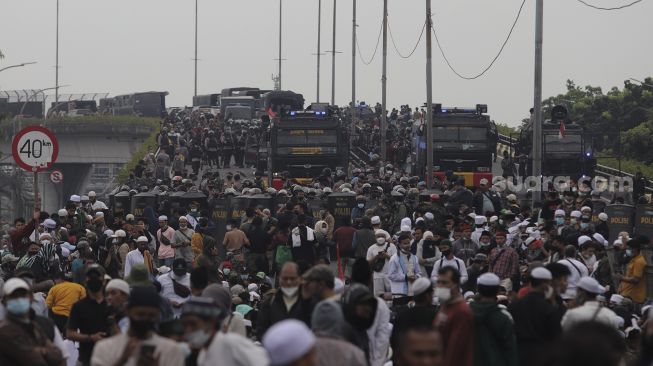 Polisi memblokade massa pendukung Rizieq Shihab di kawasan I Gusti Ngurah Rai saat akan menuju Pengadilan Negeri (PN) Jakarta Timur, Kamis (24/6/2021). [Suara.com/Angga Budhiyanto]