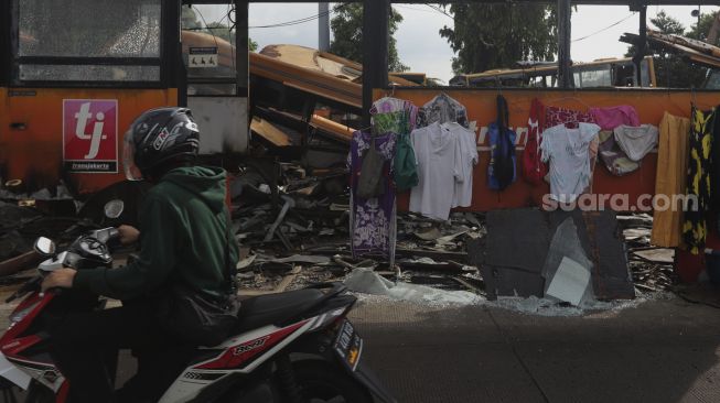 Pengendara sepeda motor melintas di depan tempat pemotongan bus Transjakarta di Terminal Pulogadung, Jakarta, Kamis (24/6/2021). [Suara.com/Angga Budhiyanto]