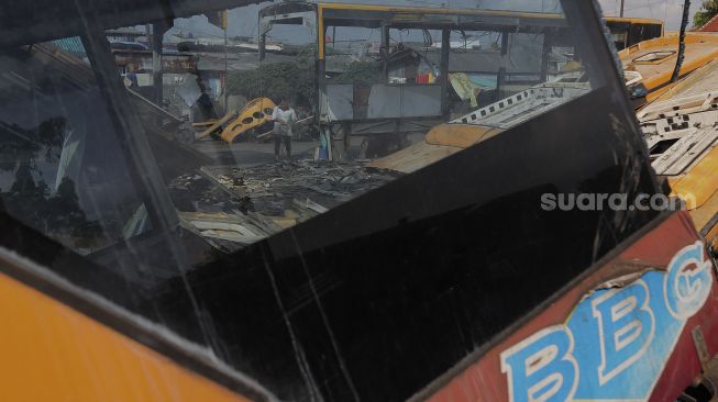 Seorang warga beraktivitas di dekat potongan bus Transjakarta di Terminal Pulogadung, Jakarta, Kamis (24/6/2021). [Suara.com/Angga Budhiyanto]