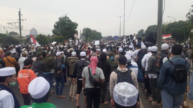Massa pendukung Habib Rizieq Shihab bertahan di kawasan Flyover Pondok Kopi pada Kamis (24/6/2021). Akibatnya akses jalan dari dan menuju Bekasi macet. [Suara.com/Yaumal]