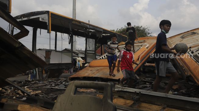 Sejumlah anak bermain di dekat potongan bus Transjakarta di Terminal Pulogadung, Jakarta, Kamis (24/6/2021). [Suara.com/Angga Budhiyanto]