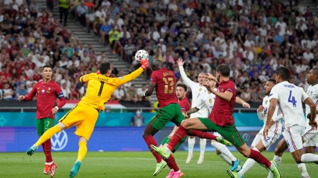 Kiper Prancis Hugo Lloris keluar dari sarangnya mencoba memotong bola saat pertandingan Portugal vs Prancis di pertandingan terakhir grup F Euro 2020, kedua tim berakhir imbang 2-2. (Foto: Darko BANDIC/AFP)