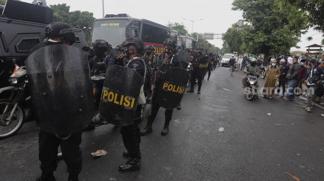 Aparat kepolisian bersiaga saat sejumlah massa pendukung Rizieq Shihab memblokade jalan di kawasan I Gusti Ngurah Rai, Jakarta, Kamis (24/6/2021). [Suara.com/Angga Budhiyanto]