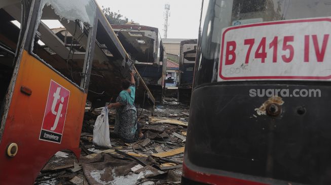 Seorang warga beraktivitas di dekat potongan bus Transjakarta di Terminal Pulogadung, Jakarta, Kamis (24/6/2021). [Suara.com/Angga Budhiyanto]