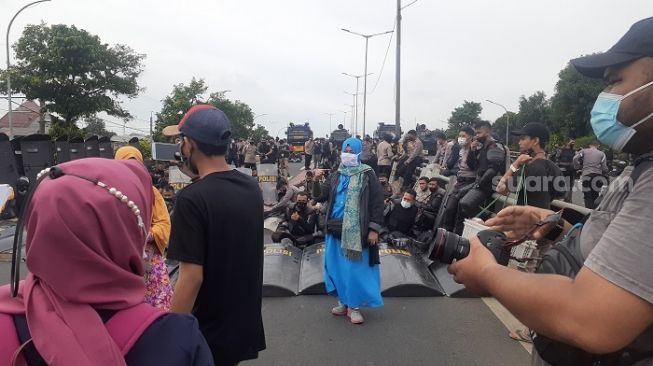 Emak-emak pendukung Habib Rizieq Shihab sempat berfoto ria sebelum membubarkan diri dengan pendemo. Foto itu diambil di depan polisi yang lelah berjaga aksi unjuk rasa. (Suara.com/Yaumal)