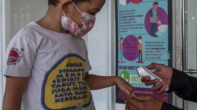 Petugas memeriksa suhu tubuh seorang anak sebelum memasuki kawasan perbelanjaan di Palu, Sulawesi Tengah, Kamis (24/6/2021). ANTARAFOTO/Basri Marzuki
