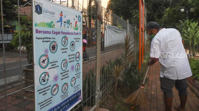 Petugas membersihkan dan merawat area bermain di RPTRA Kebon Melati, Jakarta Pusat, Jumat (25/6/2021). [Suara.com/Alfian Winanto]