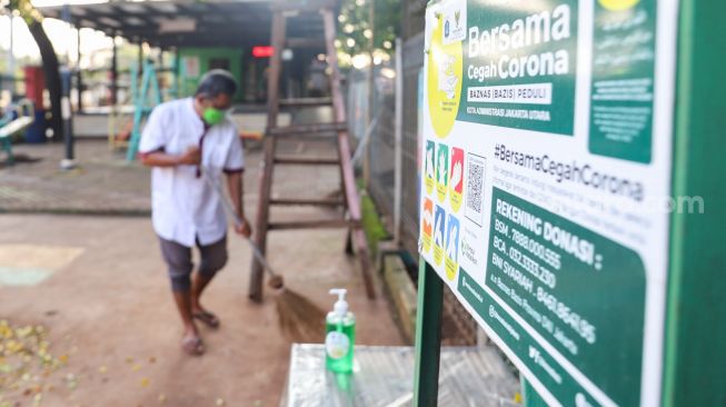 Petugas membersihkan dan merawat area bermain di RPTRA Kebon Melati, Jakarta Pusat, Jumat (25/6/2021). [Suara.com/Alfian Winanto]