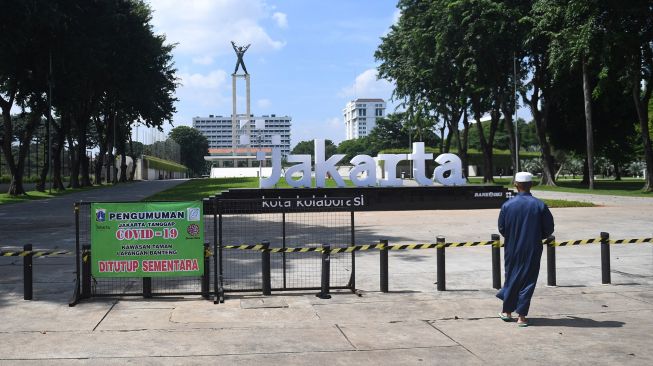 Warga melintas di dekat Taman Lapangan Banteng yang ditutup untuk sementara waktu di Jakarta, Jumat (25/6/2021).  ANTARA FOTO/Akbar Nugroho Gumay
