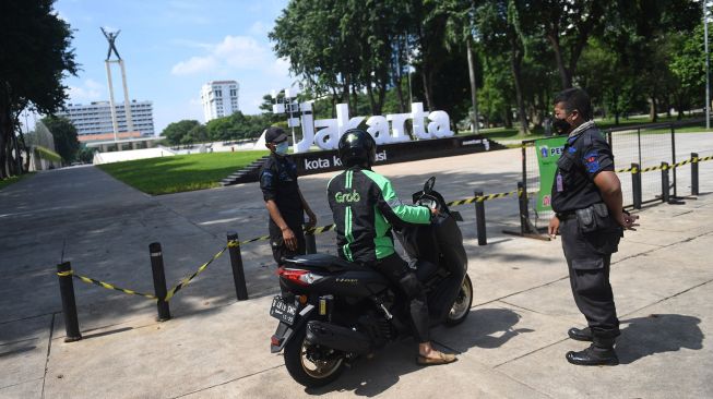 Petugas gabungan memberikan penjelasan soal ditutupnya Taman Lapangan Banteng untuk sementara kepada pengendara motor di Jakarta, Jumat (25/6/2021). ANTARA FOTO/Akbar Nugroho Gumay
