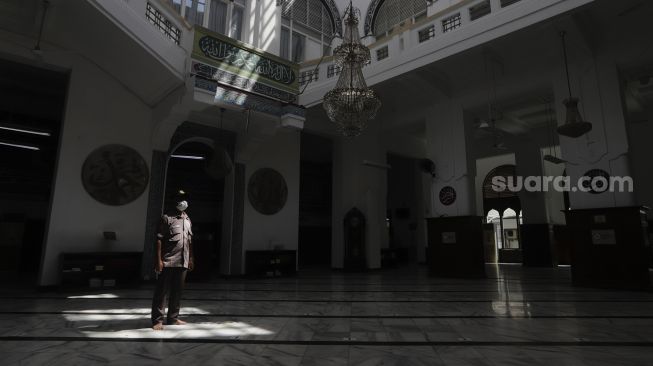 Petugas keamanan berjaga saat peniadaan sholat Jumat di Masjid Cut Meutia, Jakarta, Jumat (25/6/2021). [Suara.com/Angga Budhiyanto]